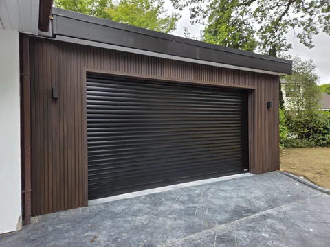 Wide black roller garage door with timber-effect vertical cladding
